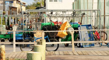 Wagons and bikes wait at the Ferry in Fire Island, NY clipart