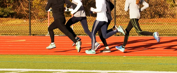 Cinco meninas correndo em uma pista vermelha — Fotografia de Stock