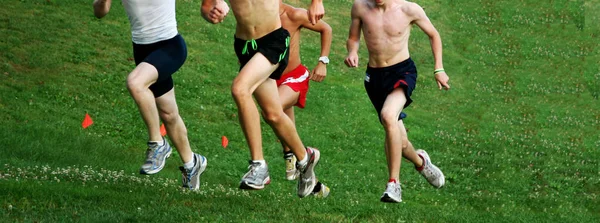 Quatro meninos correndo subida durante uma corrida cross country — Fotografia de Stock
