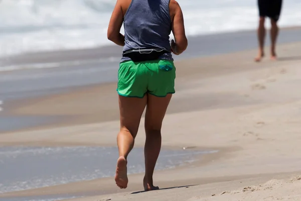 Feminino correndo descalço na praia — Fotografia de Stock