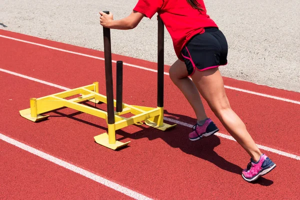 Женщина толкает желтые сани на трек на тренировке. — стоковое фото