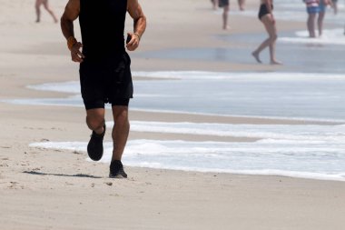 Erkek koşucu koşu kum yanındaki Atlantik Okyanusu üzerinde