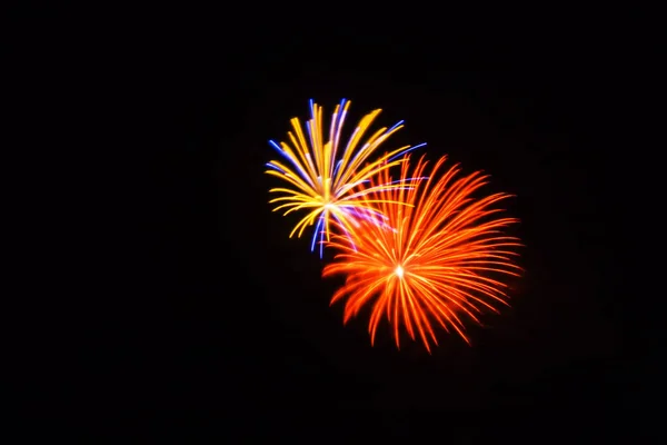 Fogos de artifício laranja, amarelo, azul e rosa brilham no céu — Fotografia de Stock