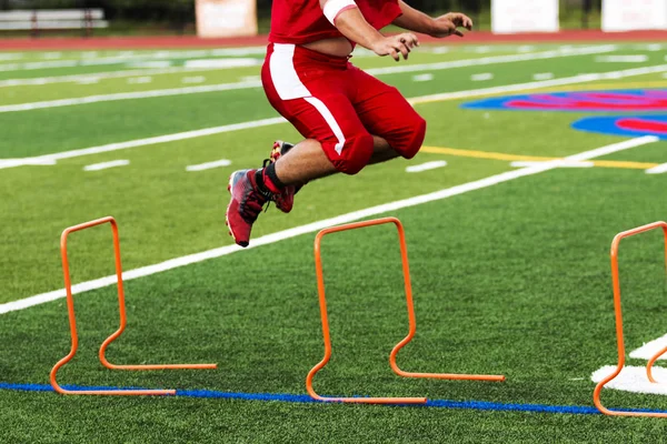 Fotbollsspelare hoppar över orange häck, — Stockfoto