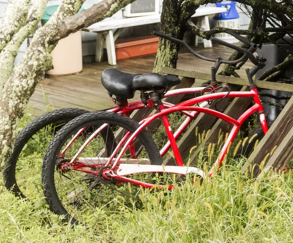 Zwei rote Fahrräder, die im hohen Gras an einem Strandhaus abgestellt sind — Stockfoto