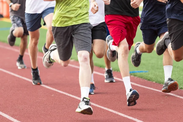 Meninos do ensino médio correndo em um grupo em uma pista vermelha — Fotografia de Stock