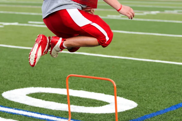 Football player cross training over orange mini hurdles — Stock Photo, Image