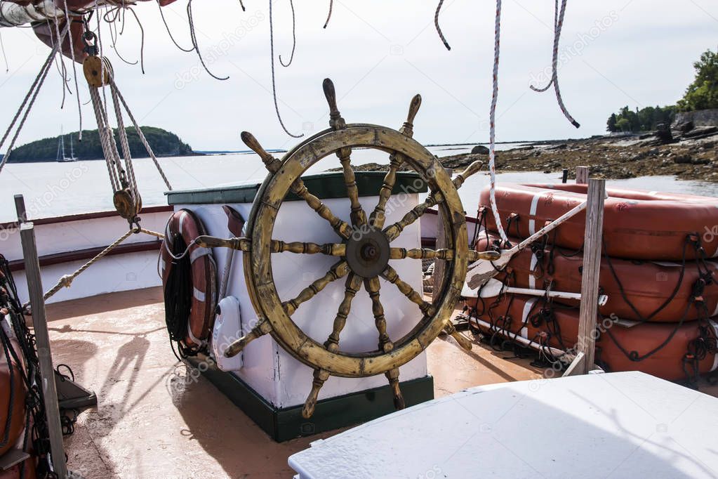 The helm of a wooden sailboat with porcupine island in the backg