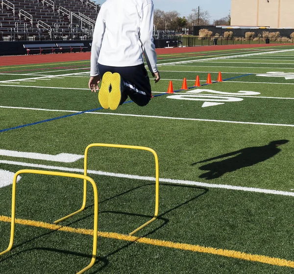 Jumping over yellow mini hurdles on a sunny day — Stock Photo, Image