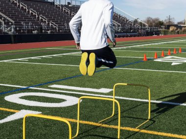 Athlete jumps over yellow hurdles making it look easy clipart