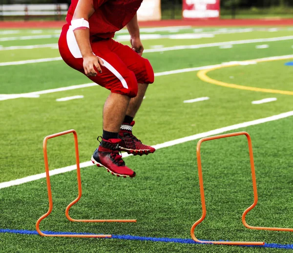 Jogador de futebol do ensino médio saltando sobre mini obstáculos — Fotografia de Stock