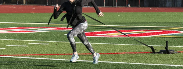 Female runner pulling a weighted sled toward camera — Stock Photo, Image