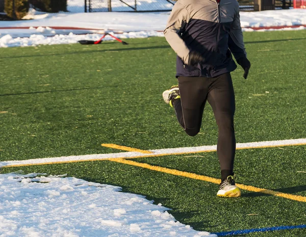 Runner on turf field with snow — Stock Photo, Image