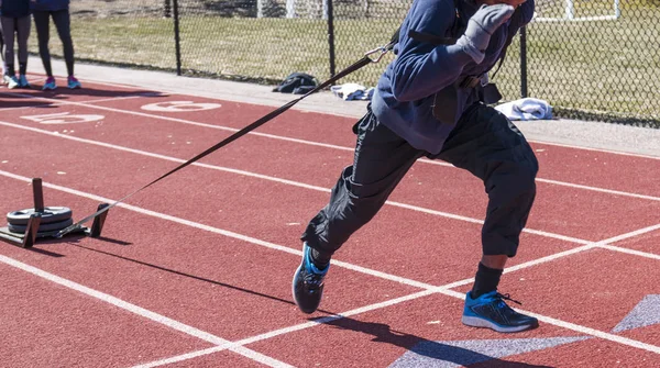 Sportler zieht einen Schlitten mit Gewichten auf einer Bahn — Stockfoto