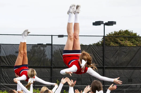 Cheerleaders fliping no ar em mãos companheiros de equipe durante a prática — Fotografia de Stock