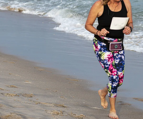 Mulheres correndo descalço na areia vestindo spandex colorido — Fotografia de Stock