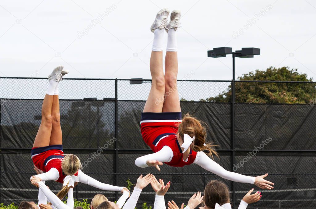 Cheerleaders fliping in the air into teammates hands during prac