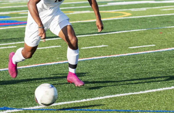 Fußballer in weißer Uniform läuft dem Ball hinterher — Stockfoto