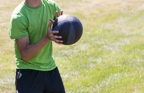 Sportowiec łapiący piłkę lekarską na polu trawy — Zdjęcie stockowe