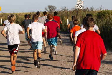 Alev Adası 'ndaki plajda saatte 30 km hızla giden bir toprak yolda birlikte koşan bir grup çocuğun arka görüntüsü..