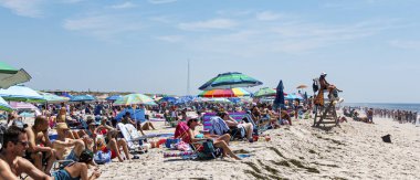 Babil, New York, Usa - 14 Temmuz 2019: Cankurtaran, arkasında okyanusa bakan kalabalık bir plajla birlikte denize bakıyor..