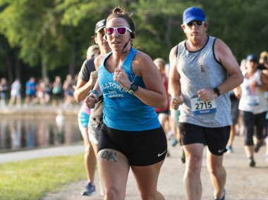 Kuzey Babylon, New York, ABD - 8 Temmuz 2019: Geleneksel yaz sierisi yarışları sırasında koşucular Belmont Gölü etrafındaki toprak yolda 5K ile yarışıyor.