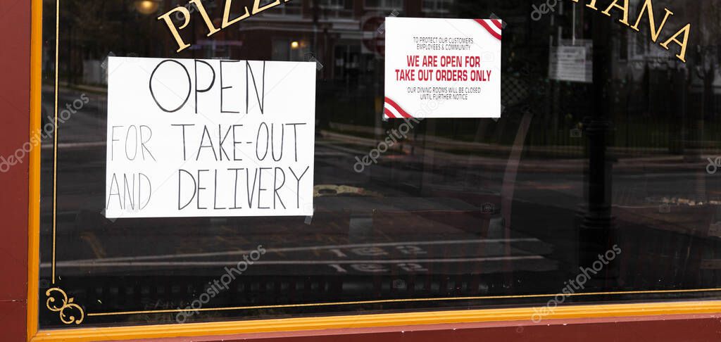 Pizza restaurant window has open for take out and delivery signs in the window because of the Coronavirus COVID-19 pandemic shutdown.