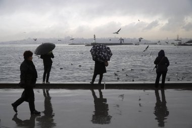 İstanbul, Türkiye-8 Mart 2018: Istanbul 'da yağmurlu bir gün, Kadiköy Sahili. Bazı insanlar iskele ile tarihi yarımada ile Istanbul peyzaj izliyor ve bir kadın yürüyüş.