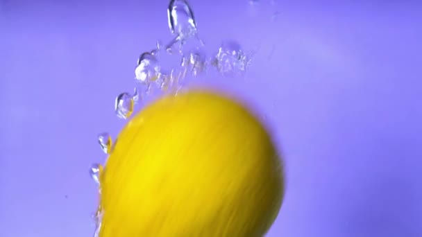 Close Slow Motion Video Orange Lemon Dropping Spinning Water Purple — Stock Video