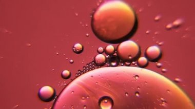 Bronz renkli yağ baloncuklarının yavaş çekimde hareket etmesi. Doğal arka plan görüntüsü olarak makrodaki su ve petrolün güzel yapısı.