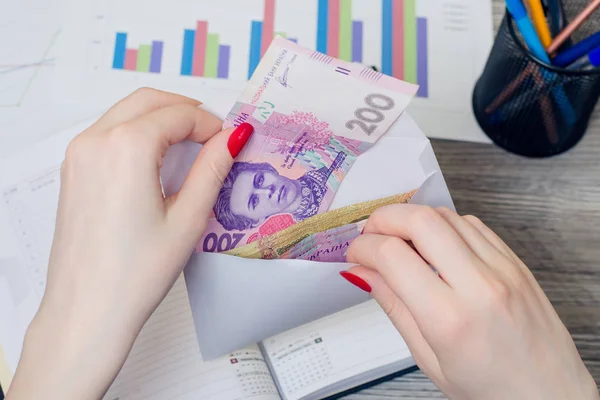 Woman\'s hands taking salary from an envelope