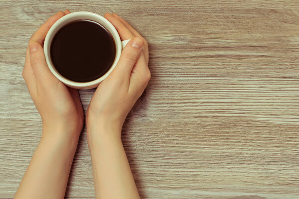 Concept of morning  coffee. Female hands holding cup of hot fres