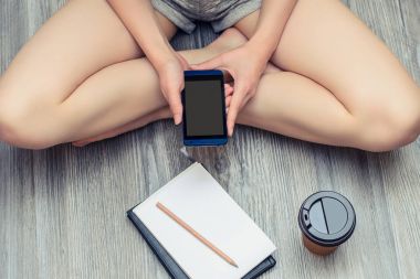 Bir r yaparken ileti alıp göndermek için cep telefonu kullanan genç kız