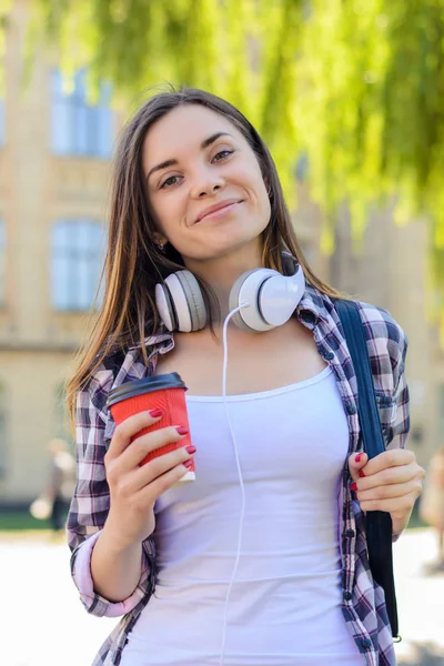 Feliz alegre y sonriente joven estudiante escuchando música y drin — Foto de Stock