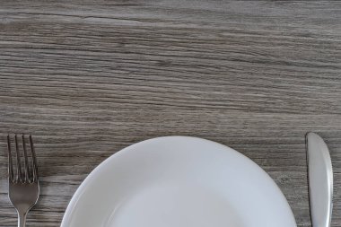 Beyaz boş levha, bıçak ve çatal gri ahşap sekmesinde üst yarısı