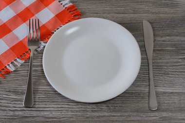 Boş beyaz yuvarlak tabak, bıçak, çatal ve masa örtüsü ahşap t