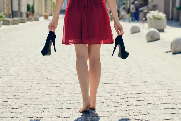 Elegante chica joven en vestido rojo con tacones altos en las manos, walkin — Foto de Stock