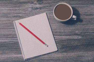 Fincan sütlü sıcak çay ve defter kalem gri ahşap masa, vintage etkisi, üstten görünüm ile