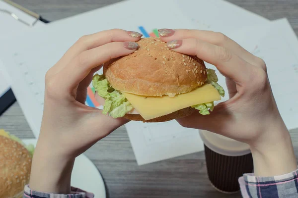 Κοντινό πλάνο φωτογραφία του ορεκτική burger στα χέρια σχετικά νέος εργαζόμενος σε — Φωτογραφία Αρχείου