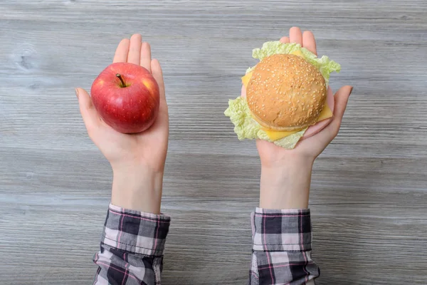 Закрыть фотографию рук с яблоком и бургером. Что выбрать ? — стоковое фото
