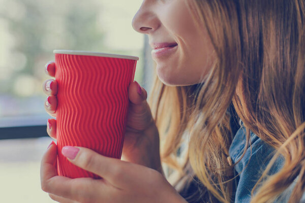 Close up cropped photo of smiling woman drinking hot fresh coffe