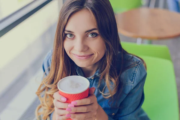 Beautiful woman with big eyes and charming smile holding a cup o