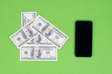 Yukarının üstünde siyah akıllı cep telefonunun resmi boş dokunmatik ekran ve kağıttan yapılmış küçük ev Amerikan parası izole edilmiş yeşil arka plan