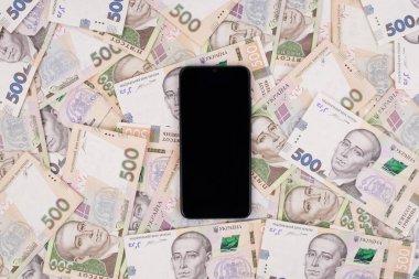 Modern teknoloji konseptini kullanarak para kazanmak. Akıllı telefonun fotokopi alanı boş, izole edilmiş para birimi arkaplanı görüntüsünün üzerinde