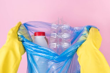 Yakından doğranmış, el ele tutuşurken çekilmiş bir fotoğraf. İçi plastik şeylerle dolu, izole edilmiş bir çöp torbası.