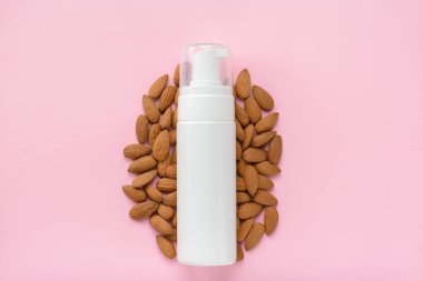 Vitaminlerle zenginleştirilmiş vücut losyonu organik mineraller konsepti. Yukarının üstünde badem fıstıklı düz bir şişe fotoğrafı var.