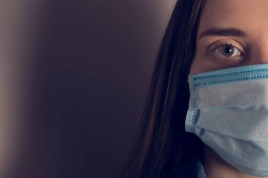 2019 ncov salgını konsepti. Yüz maskesi takan kötü bir insanın korku dolu korku dolu fotoğrafının kesilip kesilmiş hali. Mesaj için boş bir yeri olan gri, koyu bir arkaplan.