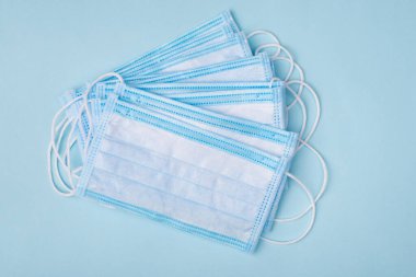 Coronavirus panik eksikliği konsepti. Yukarıda, boş boşluklu ve arka planda izole edilmiş tıbbi maske yığınının yakın görünüm fotoğrafı