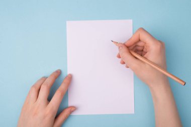 Başvuru formu yazılıyor ya da özgeçmiş yazılıyor. Yukarıdaki ilk kişi, boş arkaplan üzerine izole edilmiş notlar almak için tahta kalem kullanan ellerin yakın görüntüsü.
