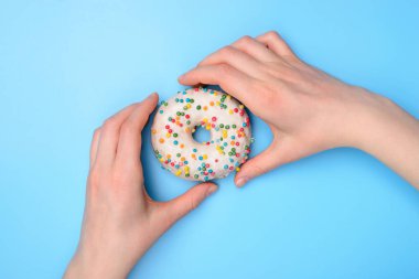 Yukarda düz düz bir tabaka üzerinde uzanır. Yakın çekim fotoğrafında ellerin lezzetli taze şekerli çörekleri alırken pastel renkli masa arkasında izole bir şekilde yemeye hazır olduğu görülüyor.